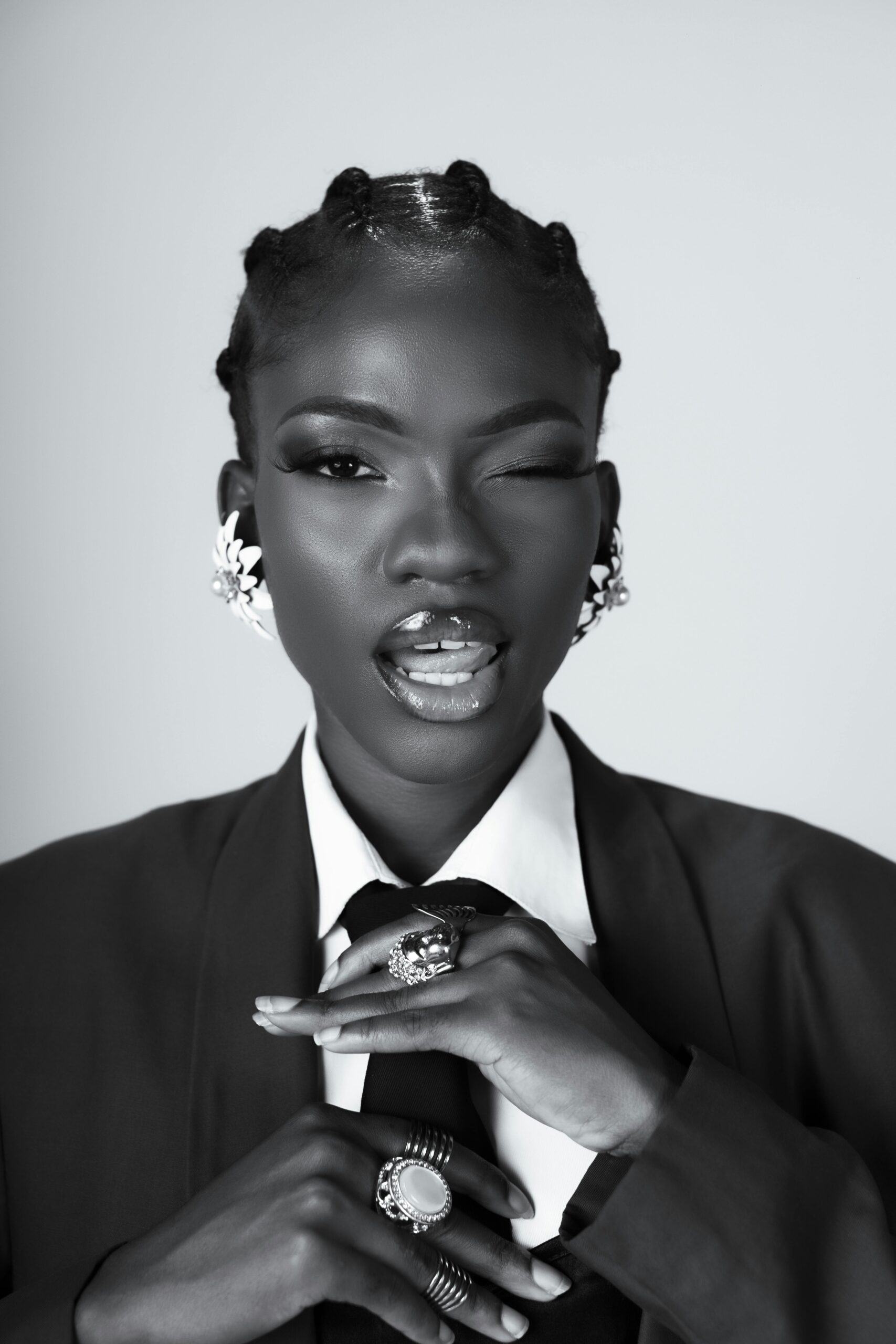 A bold fashion portrait of a woman in monochrome, wearing jewelry and a necktie.